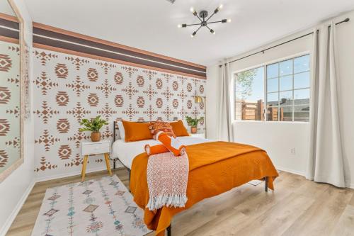 a bedroom with a bed with orange sheets and a window at Hot Tub, Games, King Bed, Fire Pit, BBQ Grill, minutes from National Park and Views in Joshua Tree