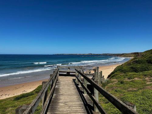 a wooden boardwalk leading to a beach with the ocean at Blue Bay View Surf & Sauna Stay in Surf Beach