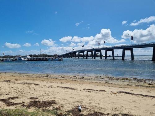 a bridge over the water next to a beach at Blue Bay View Surf & Sauna Stay in Surf Beach