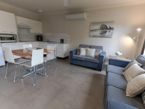 a living room with a table and a blue couch at Martys Little Beach NO. 4 Ground Floor Apartment with Heated Pool access in Nelson Bay