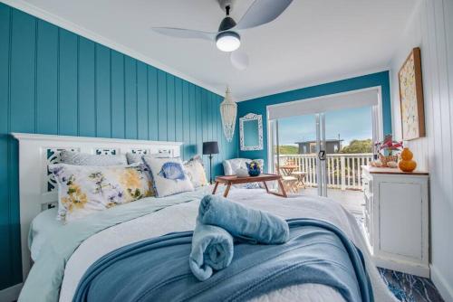 a bedroom with a bed with a blue wall at Blue Bay View Surf & Sauna Stay in Surf Beach