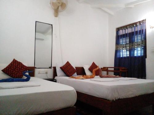 two beds in a room with a mirror at Sigiri Neo Homestay in Sigiriya