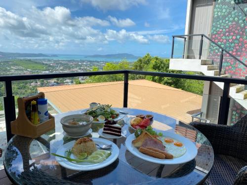 シャロンにあるPhuket View Coffee and Resortのバルコニーにテーブルと2皿の食べ物