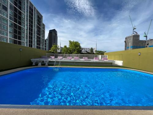 a large blue swimming pool with chairs and buildings at The Victory Residences Bangkok in Bangkok