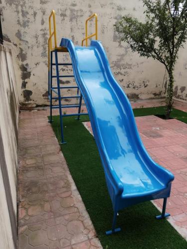 a blue slide in a playground with green grass at Candle Wood in Bhurban