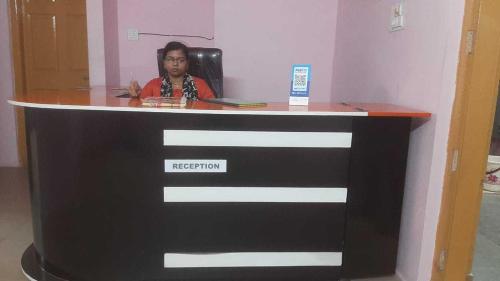 een vrouw zit bij de receptie bij OYO Aaradhya Hotel &restaurant in Parādīp Garh