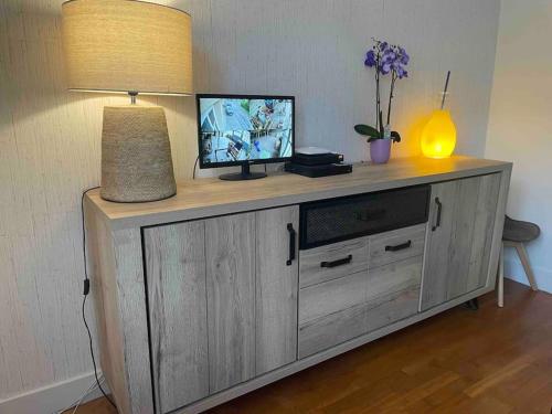 a television on top of a wooden cabinet with a lamp at Manornella, beaux volumes, grand garage idéal Mas du Clos in Aubusson