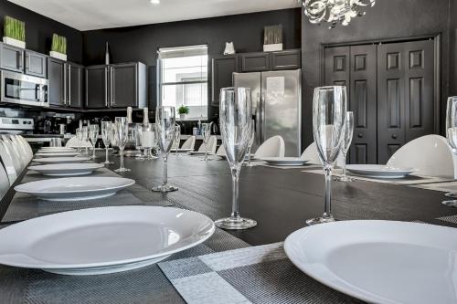 a dining room with a long table with wine glasses at 14 Room DisneyEstate by AmericanVacationliving in Davenport