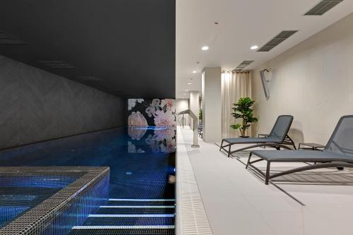 a hallway with a swimming pool and chairs in a building at GRANO APARTMENTS Gdańsk Old Town SPA & Wellness - GRANO APARTMENTS Gdańsk Residence SPA & Wellness in Gdańsk