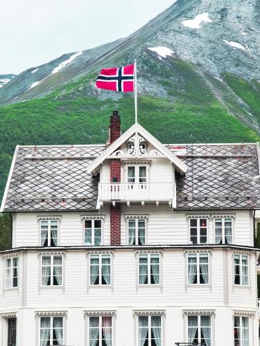 a flag on top of a white building with a mountain at Sylte Hotell, Valldal in Valldal