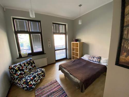 Sopot Lodge في سوبوت: غرفة نوم بسرير وكرسي ونوافذ