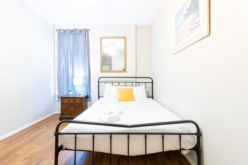 a white bedroom with a bed with a yellow pillow at Sunny Sweetheart-Front Apartment near Riverwalk in Columbus