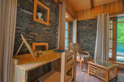 una oficina con escritorio de madera y pared de piedra en SaffronStays The Elements, en Kulu
