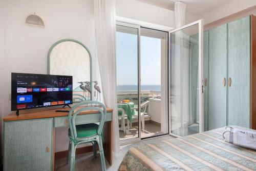 a bedroom with a desk with a computer and a balcony at Hotel Cigno D'Oro in Riccione