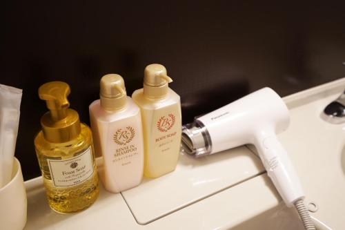 two bottles of soap and a blow dryer on a sink at Plaza In Kanku Hotel in Izumi-Sano