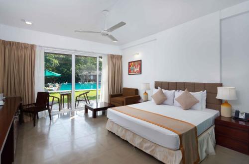 a hotel room with a bed and a dining room at South Lake Resort Koggala in Koggala
