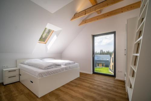 a white bedroom with a bed and a window at Holiday House U Hájenky 12P Lipno Home in Lipno nad Vltavou