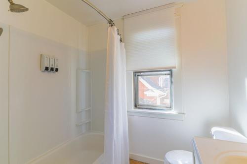 La salle de bains blanche est pourvue d'une baignoire et d'une fenêtre. dans l'établissement Modern, Spacious 3 Bedroom Getaway, à Saint Paul