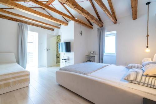 - une chambre blanche avec un grand lit et des plafonds en bois dans l'établissement House Franulich, à Stara Baška