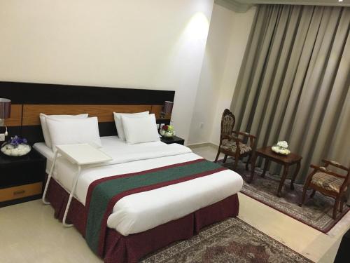 a hotel room with a large bed and two chairs at Muscat International Hotel Plaza in Salalah