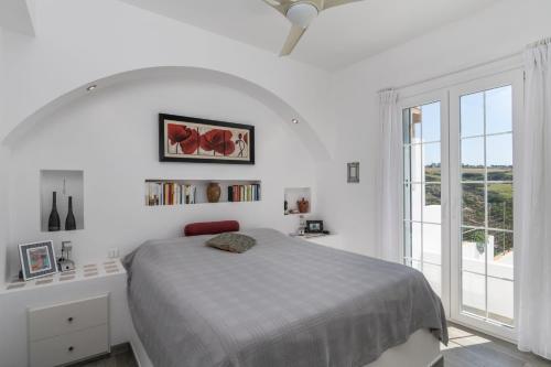 a white bedroom with a bed and a window at Casa Mia Milos in Paleochori