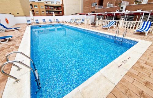a large swimming pool with blue chairs in a building at Hotel Santa Cecilia in Ciudad Real