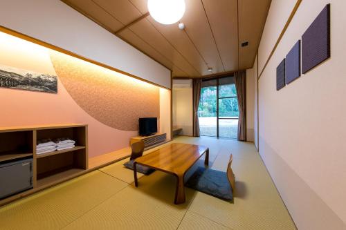 a living room with a wooden table and a tv at Sennomori in Ise