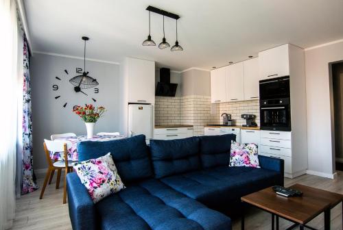 Il comprend un salon avec un canapé bleu et une cuisine. dans l'établissement Apartament Cztery Pory Roku w Giżycku, à Giżycko