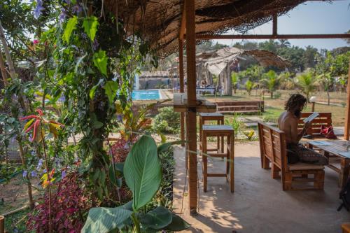 a woman sitting at a table in a garden at Radhika Eco Resort(Odonata) in Arambol