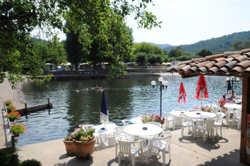 a group of tables and chairs in front of a lake at Charmant Appart cosy + terrasse in Bessèges