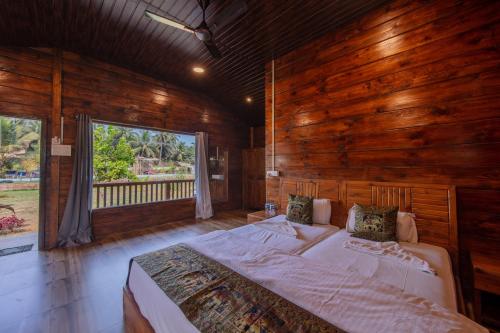 a large bed in a wooden room with a window at Radhika Eco Resort(Odonata) in Arambol