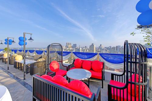 einen Balkon mit roten Stühlen und Tischen sowie Stadtblick in der Unterkunft Poulo Wai Hotel & Apartment in Phnom Penh