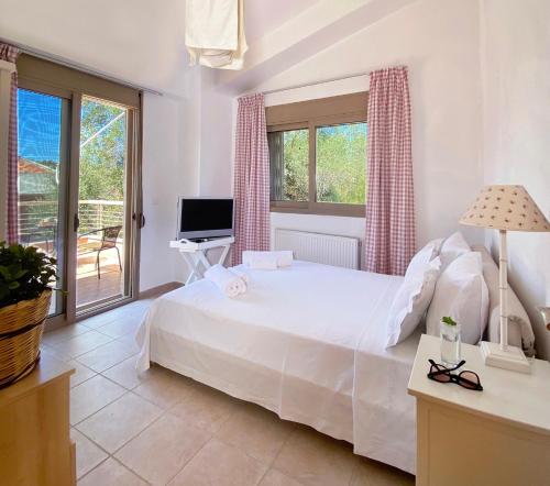 a bedroom with a large white bed and a television at Villa Julia in Sani Beach