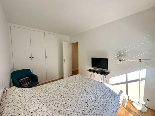 - une chambre avec un lit, une télévision et une chaise dans l'établissement Cosy, calm 70m2, 2 bedroom flat., à Paris