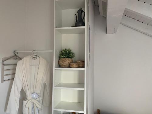 einen weißen Schrank mit einem weißen Bademantel und einer Pflanze in der Unterkunft Ruhige Wohnung an der Uni in Düsseldorf
