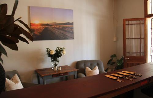 a dining room with a table and chairs and a painting at @karoo Guesthouse in Graaff-Reinet