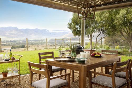einen Tisch und Stühle auf einer Terrasse mit Aussicht in der Unterkunft Boschendal Farm Estate in Franschhoek