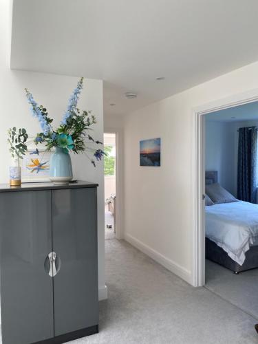 a bedroom with a bed and a vase of flowers on a cabinet at SUMMERPLACE in Padstow
