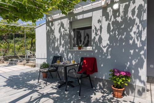 een patio met 2 stoelen, een tafel en een raam bij Apartments Roza in Mlini