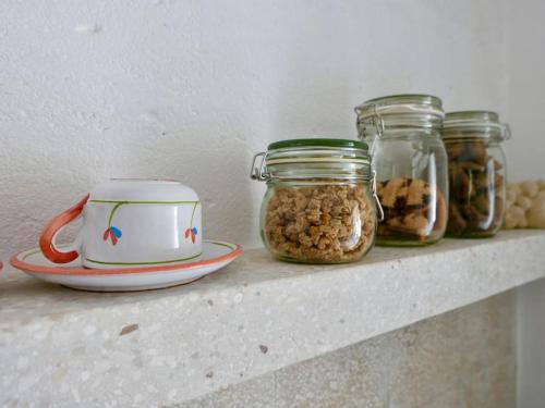 a shelf with three jars of nuts and a tea pot at Masseria Pezze Galere-La Casa del Fico con piscina idromassaggio privata in Fasano