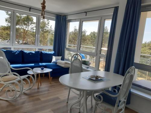 - un salon avec un canapé bleu, des fauteuils et des fenêtres dans l'établissement Apartamenty Pisakowe - Apartament Śledzik, à Rowy