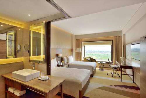 ラーイプルにあるCourtyard by Marriott Raipurのベッドとシンク付きのホテルルーム