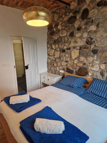 a bedroom with two beds and a stone wall at Sobe Lotrist in Radovljica
