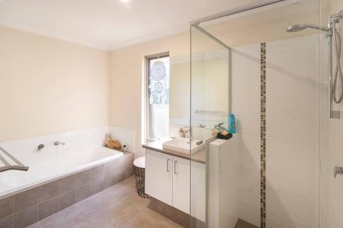 Un baño con bañera, lavabo y ducha. en Duke Cottage - pet friendly near beach., en Busselton