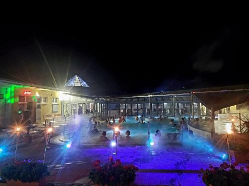 a group of people sitting around a pool at night at Penzión Florens, Nesvady in Nesvady