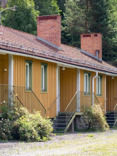 uma casa amarela com uma chaminé de tijolo e escadas em Sikfors Gästhus em Hällefors