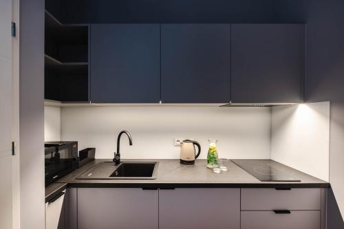 a kitchen with black cabinets and a sink at By Monte Apartment in Sopot