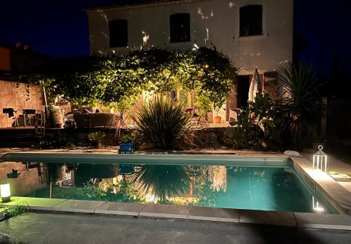 a swimming pool in front of a house at night at Chambre et table d hotes chez Dom in Sainte-Cécile-les-Vignes