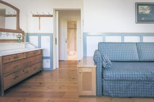a bedroom with a bed and a dresser and a blue couch at Parkhotel Holzner in Soprabolzano