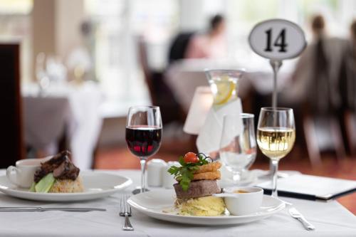 a table with two plates of food and wine glasses at Ballina Manor Hotel in Ballina
